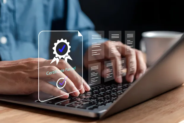 Hands typing on laptop keyboard, overlay shows "Certificate Passed" verification symbol. Digital concept representing certification or compliance validation.